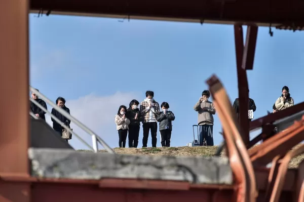 Personas guardan un minuto de silencio en el 14º aniversario del terremoto, tsunami y desastre nuclear de 2011.